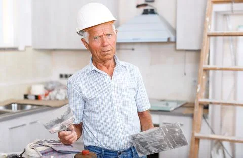 Puzzled worker checking plaster work indoors Stockfoto's