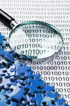 Puzzles and magnifying glass on a binary code 库存照片