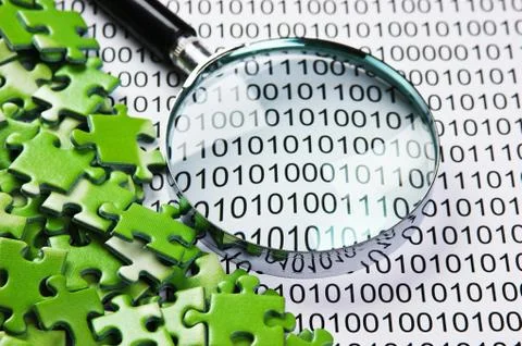 Puzzles and magnifying glass on a binary code 库存照片