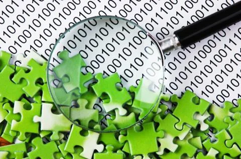 Puzzles and magnifying glass on a binary code 库存照片