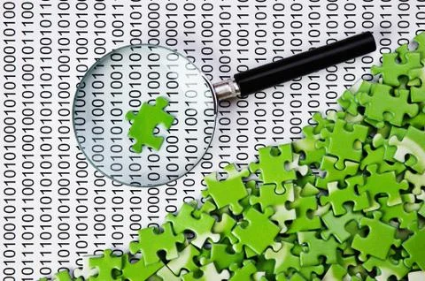 Puzzles and magnifying glass on a binary code 库存照片