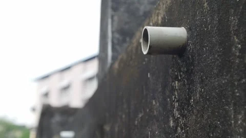 PVC pipe protruding from dark mossy concrete wall Vídeos de archivo 334413469