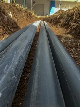 Pvc pipes laid in parallel inside a trench in the ground Stock Photos