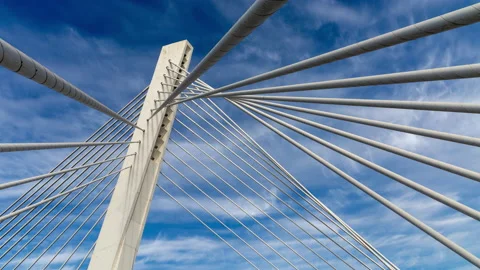 Pylon of a cable stayed bridge under fast moving white clouds in blue sky Stock Footage 145375096