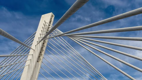Pylon of a cable stayed bridge under fast moving white clouds in blue sky Stock Footage 145714811