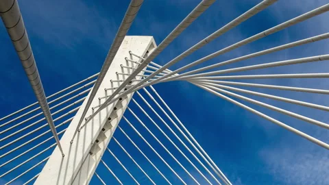 Pylon of a cable stayed bridge under fast moving white clouds in blue sky Stock Footage 145717620