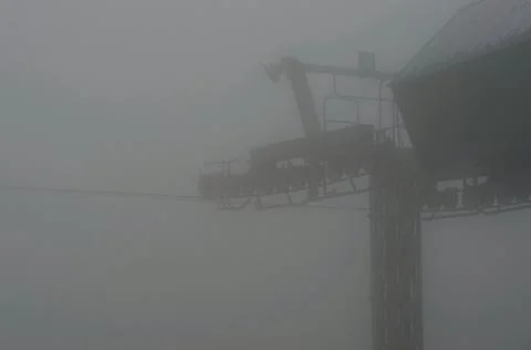The pylon, wheels and cable of a cable-car covered in fog. Stock Photos