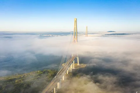 The pylons of the giant cable-stayed bridge rise above the seaside morning fog Foto stock