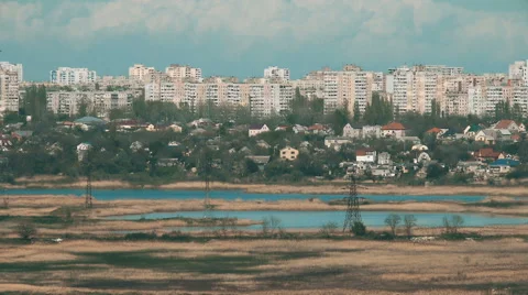 Pylons of the old electricity in fields and a lake with buildings on background Stock Footage 64992726