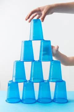 Pyramid of blue plastic cups. Set for party. Children hands Stock-Fotos