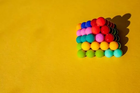 Pyramid of multi-colored bright plastic parts with shadow on yellow backgroun Stock Photos