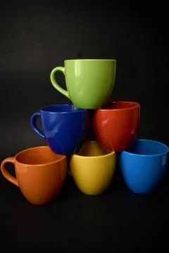 Pyramid of multi-colored cups for coffee on a black background. Stock Photos