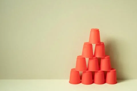 Pyramid of red plastic cups on desk. khaki beige background Stock Photos
