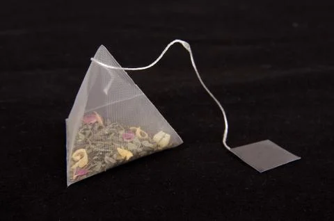 Pyramid shape teabag on the dark background 스톡 사진