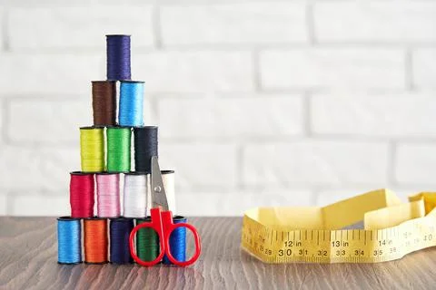 Pyramid of spools of multi-colored sewing threads, scissors, measuring tape Stock Photos