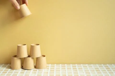 Pyramid stack of brown cup on desk. yellow background Фото