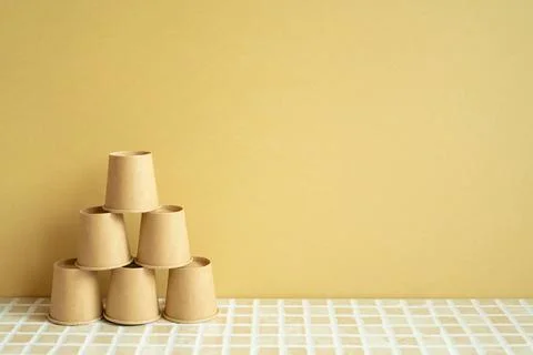 Pyramid stack of brown cup on desk. yellow background. business develop ac... 스톡 사진