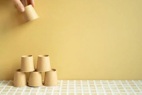 Pyramid stack of brown cup on desk. yellow background. business develop ac... Stock Photos