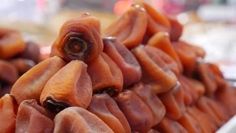 Pyramid stack of dried persimmons arranged carefully on a market selling surface Stock Footage 335442993