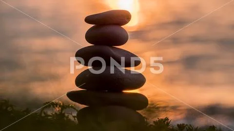 A pyramid of stones against the backdrop of the sea and the glare from the Stock Photos
