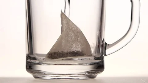 Pyramid tea bag in cup is poured over boiling water Stock Footage 73853994