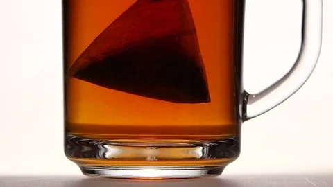 Pyramid tea bag in сup with hot water. Close ups Stock Footage 73853650