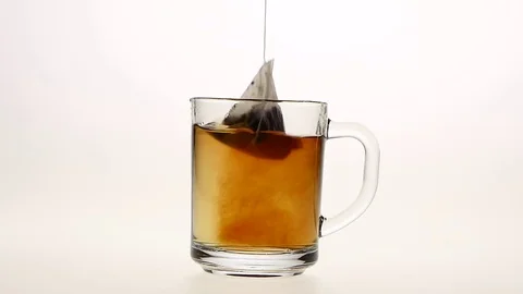 Pyramid tea bag in сup with hot water, white background Stock Footage 73855718