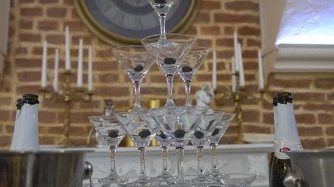 Pyramid of wine glasses or tower of champagne with wall clock on background Video stock 107610529