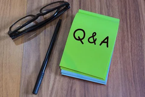 QA with punctuation mark text on green notepad with glasses and pen on a desk Stock Photos