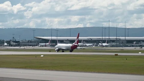 Qantas aircraft turning and taxiing, hills in background Stock Footage 195313118
