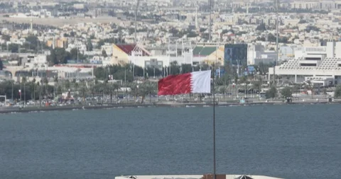 Qatar flag waving at wind in Doha Stockbeeldmateriaal 121714089