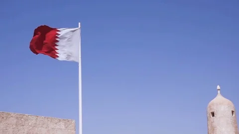 Qatari flag blowing in the wind with details of buildings behind Stock Footage 76936143
