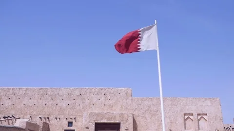 Qatari flag flapping in the wind against traditional building front Stock-Footage 76936152