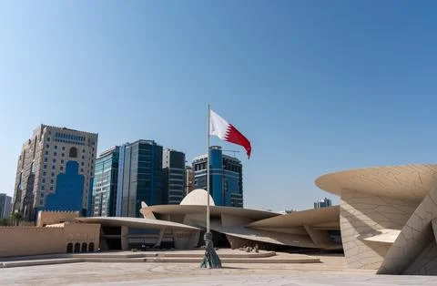 Qatari flag flying in front of the National Museum of Qatar. Stock Photos