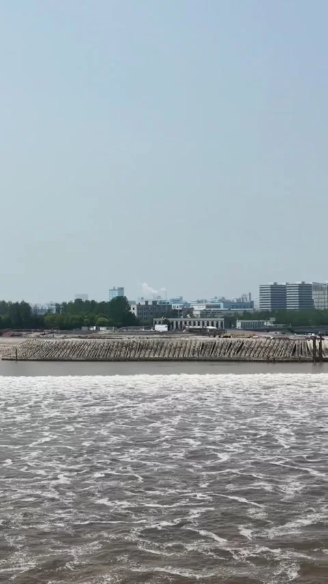 Qiantang River Tidal Bore Rushing Past Urban Bank in Hangzhou, Zhejiang, China Stockbeeldmateriaal 337385244