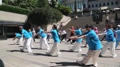 A qigong instructor teaching a stretching move to a group of people Stock Footage 51332663