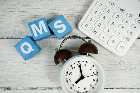 QMS (Quality Management System) text with alarm clock and calculator on woo.. Foto stock