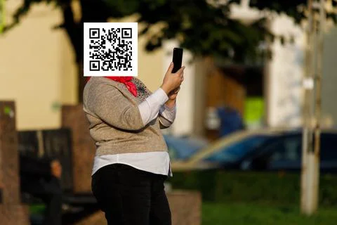 Qr code on the face of a person holding a phone in his hand Stock Photos