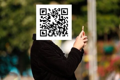 Qr code on the face of a person holding a phone in his hand Stock Photos