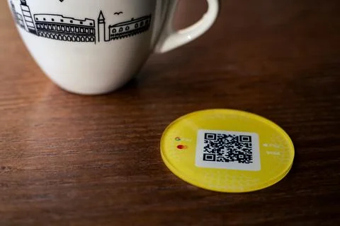 A QR code payment token on a wooden table next to a white coffee mug Stock Photos