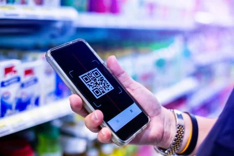 Qr code tag on smartphone with blurry products on shelves in supermarkets. Sc Stock Photos