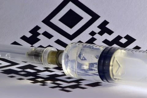 QR-code of vaccination shines through a disposable plastic syringe Stock Photos