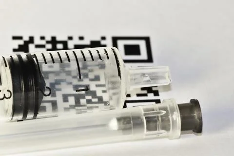 QR-code of vaccination shines through a disposable plastic syringe Stock Photos