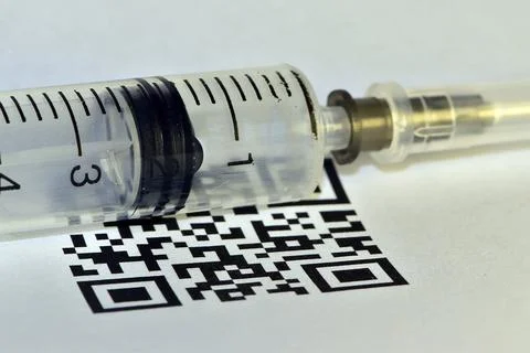QR-code of vaccination shines through a disposable plastic syringe Stock Photos