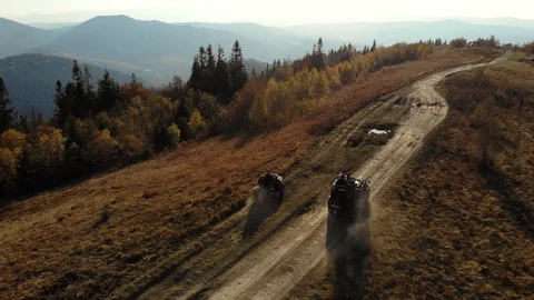 Quad bikes and SUV going on mountaint road. Sunny Autumn daytime. Aerial view. Stock Footage 120423102