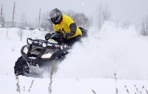 The quad bike's driver rides over snow track Stock Photos