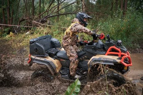 Quad rider jumping on a muddy forest trail. Stock Photos