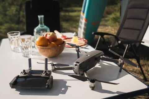 The quadcopter and the remote control are on the table near the campsite Foto stock
