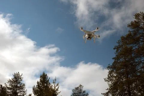 Quadcopter on the background of forest and clouds. Stock Photos