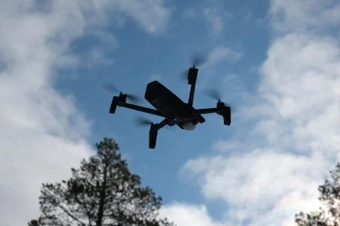 Quadcopter on the background of forest and clouds. Stock Photos